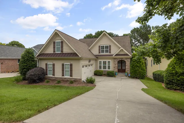 Large suburban home with a green lawn, shrubs, and a driveway.